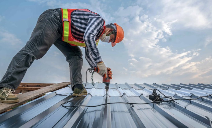 Roofing contractor securing metal roof panel with drill